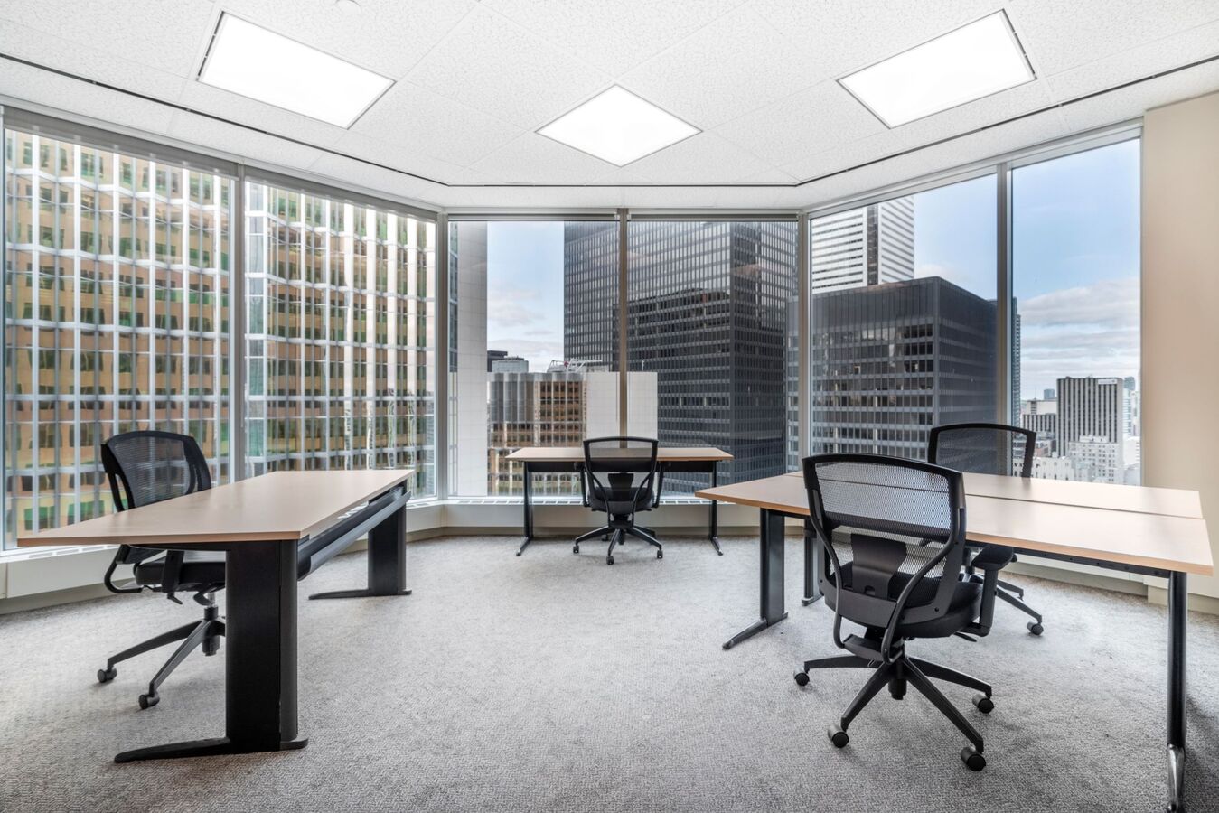 BOMA BEST - A leased corner office with large windows and city views, containing three desks with black chairs and minimal decor, offers an inviting workspace for discerning tenants.